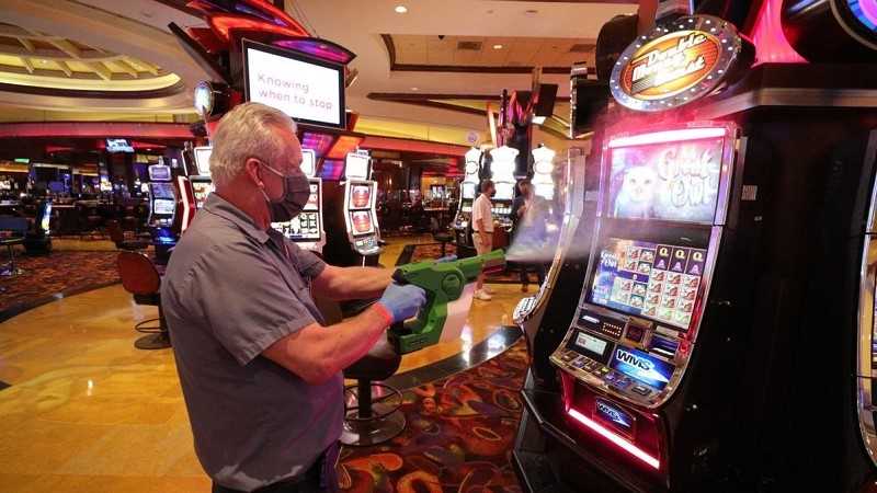 a casino worker sanitizing a gaming machine in an atlantic city casino