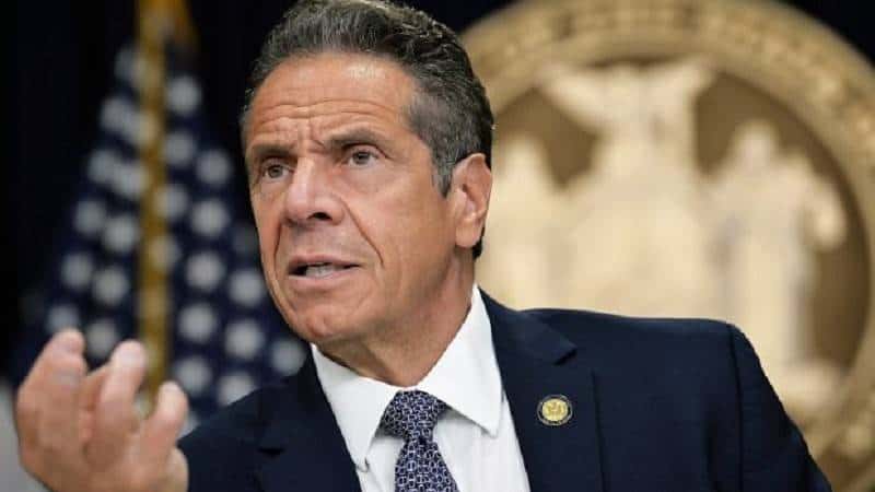 new york governor andrew cuomo at the podium scowling and making a claw like hand gesture