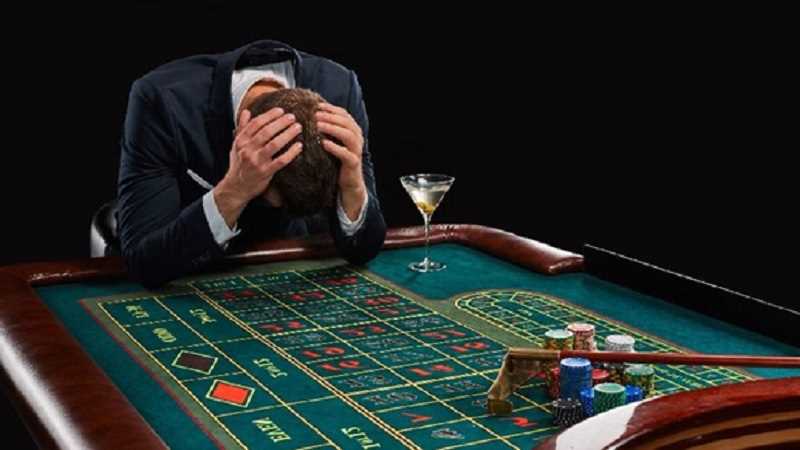 man with his head in his hands losing at a casino game