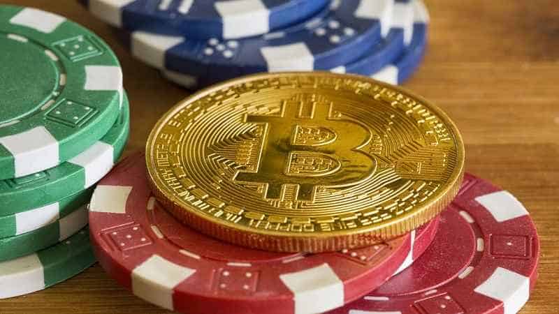 a gold bitcoin token on top of poker chips