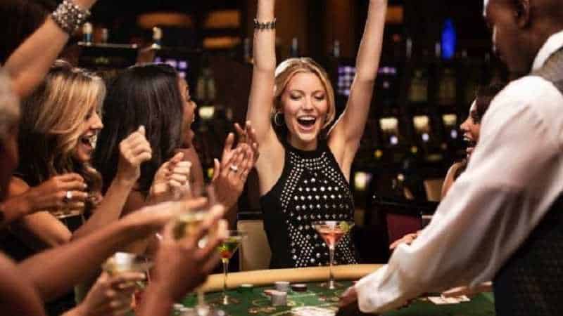 woman with arms raised winning at a casino table game